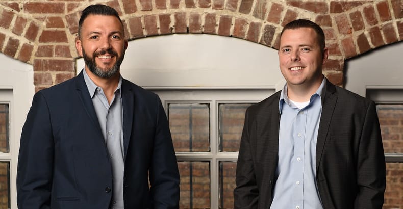 two men in suits posing for a photo